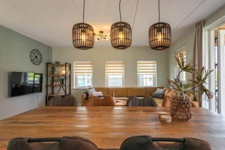 a living room with a large wooden table and chandeliers at Hello Zeeland - vakantiewoning Knuitershoek 86 in Kloosterzande