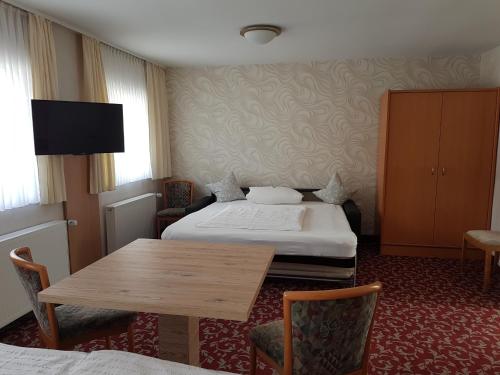 a hotel room with two beds and a table at Hotel Garni Fuhrhop in Bad Karlshafen