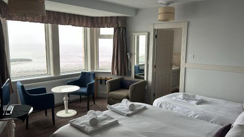 a hotel room with two beds and a table and chairs at The Strathmore Hotel in Morecambe