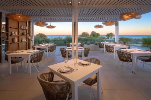 a restaurant with tables and chairs and a view of the ocean at Gennadi Grand Resort in Gennadi
