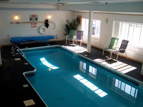 a large swimming pool in a room with chairs at Baxter Park Inn in Millinocket