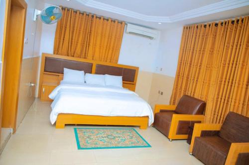 a bedroom with a large bed and a chair at CALBERT LODGE in Abuja