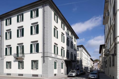 un edificio bianco con finestre verdi su una strada di Anglo American Hotel Florence, Curio Collection By Hilton a Firenze