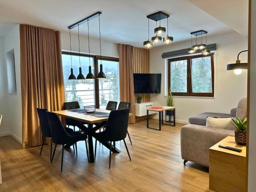 sala de estar con mesa, sillas y sofá en Apartamenty Satoła Ciągłówka en Zakopane