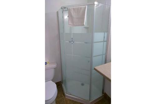 a bathroom with a glass shower with a toilet at Colonial Inn Extended Stay by OYO New Ulm in New Ulm