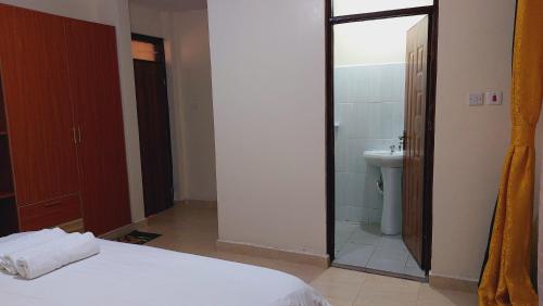 a bedroom with a bed and a bathroom with a toilet at MaGiK Furnished All Ensuite 2 bedroom Apartment in Nyeri