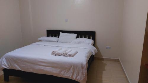 ein Bett mit weißer Bettwäsche und Kissen darauf in der Unterkunft MaGiK Furnished All Ensuite 2 bedroom Apartment in Nyeri
