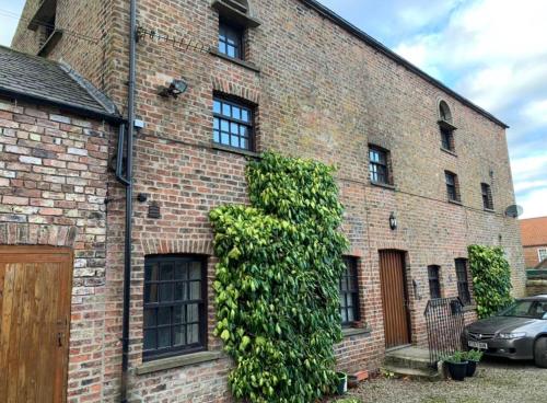 a brick building with a large green bush at The Carriage House, Bilbrough York Sleeps 24 in Bilbrough