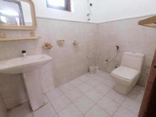 a white bathroom with a toilet and a sink at Sunshine Guest House in Polonnaruwa