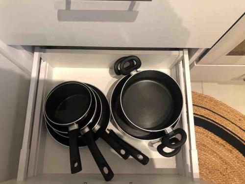 two pots and pans in a glass cabinet at Les Voiles Blanches T2 luxe à 100m de la plage in Leucate