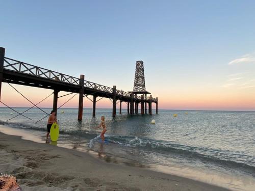 a group of people standing on the beach near a pier at Les Voiles Blanches T2 luxe à 100m de la plage in Leucate