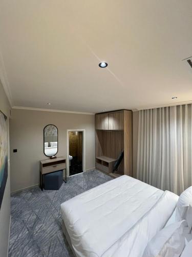 a bedroom with a large white bed and a television at Villa Park in Al Khobar