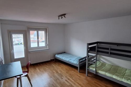Cette chambre comprend des lits superposés, une table et une chaise. dans l'établissement Apt Nuits au pied du Phare, à Calais