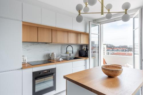 - une cuisine avec des placards blancs et un bol en bois sur un comptoir dans l'établissement Alamanda - Appartement 6ème arrondissement de Lyon, à Lyon