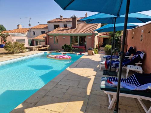 una piscina con sillas y sombrillas junto a una casa en Villa Des Plages- Piscine et spa privatifs-14pers, en Olonne-sur-Mer
