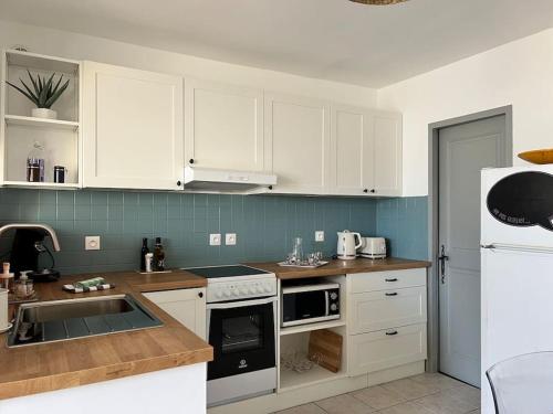 a kitchen with white cabinets and a white refrigerator at Le cocon in Notre-Dame-de-la-Rouvière
