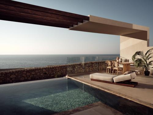 a villa with a swimming pool with a view of the ocean at The Royal Senses Resort & Spa Crete, Curio Collection by Hilton in Panormos Rethymno