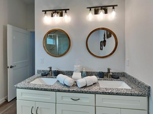 a bathroom with two sinks and two mirrors at Oasis On The Bay in Rockport