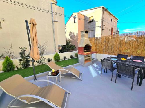 a patio with a table and chairs and a fireplace at Apartmani Krnić in Šibenik