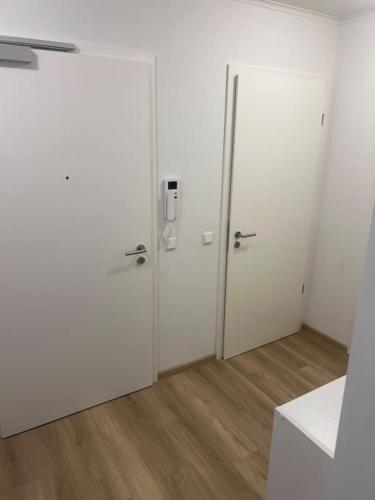 - deux portes blanches dans une chambre dotée de parquet dans l'établissement Schönes Apartment Nähe HBF, à Brême