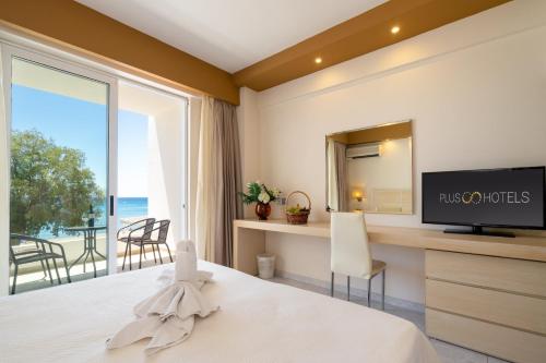 a bedroom with a bed and a tv and a balcony at Kamari Beach in Lardos