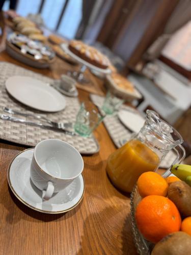 a wooden table with plates and cups and oranges on it at B&B La Baita "monolocale ad uso esclusivo" in Fonni