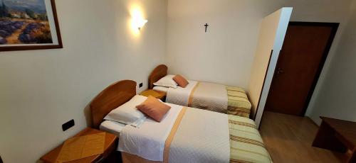 two beds in a room with a cross on the wall at Apartments and Rooms Laura in Pazin