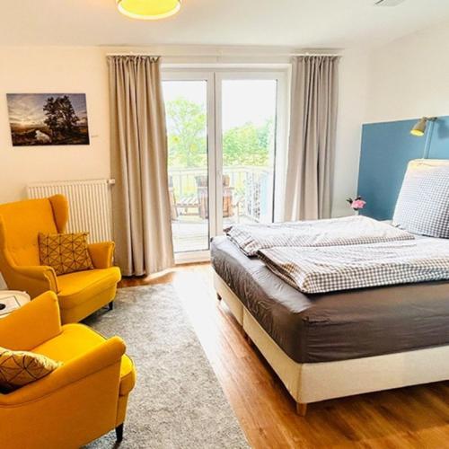 a bedroom with a bed and a yellow chair at Appartement Seerose in Poppenbüll