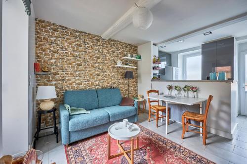 - un salon avec un canapé bleu et un mur en briques dans l'établissement Cottage Côté Mer - A 1km de la plage, à Courseulles-sur-Mer