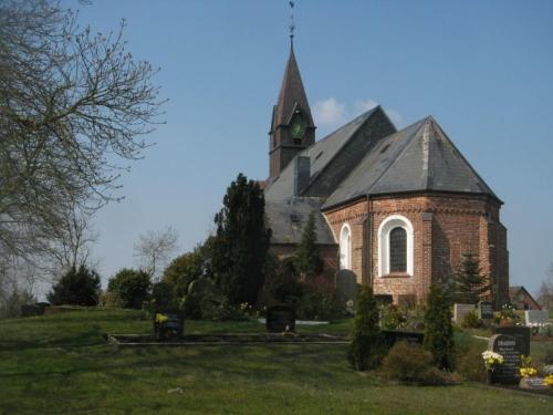 a church with a steeple on top of a field at Appartement Seerose in Poppenbüll