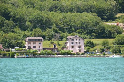 a group of houses on the shore of a body of water at Le Coin des Cygnes et le Nid du Lac, 2 appartements au bord du lac d'Annecy avec plage privée in Doussard