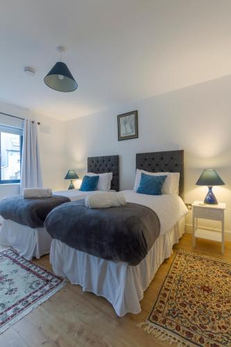 two beds in a bedroom with two lamps and a rug at Renada Cottage in Dingle