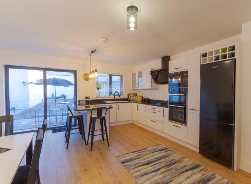 eine Küche mit einem schwarzen Kühlschrank und einem Tisch mit Stühlen in der Unterkunft Renada Cottage in Dingle