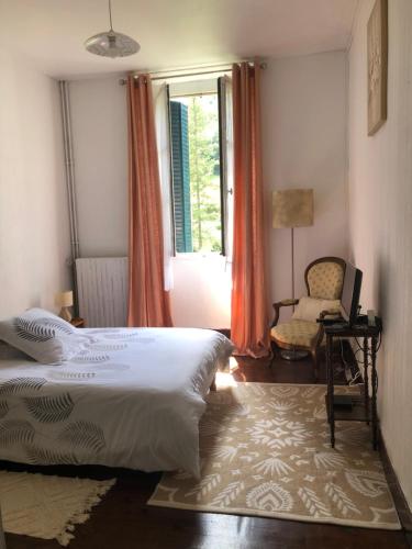 Villa Julia في Capvern: غرفة نوم بسرير وكرسي ونافذة