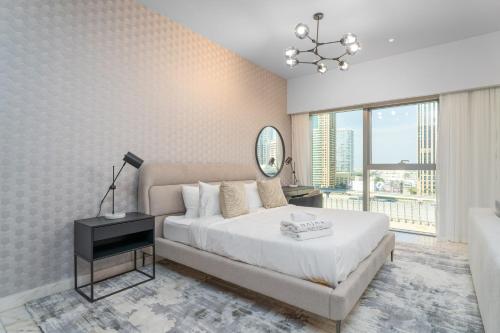 a white bedroom with a bed and a mirror at Nasma Luxury Stays - Modern Studio Apartment with City View In DIFC in Dubai