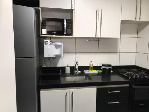 eine Küche mit einer Spüle und einer Mikrowelle in der Unterkunft Quarto no Dubai Residence in São Luís