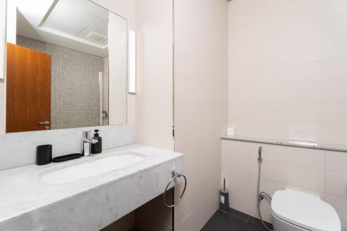 Nasma Luxury Stays - Modern Studio Apartment with City View In DIFC في دبي: حمام أبيض مع حوض ومرحاض