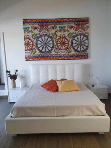 a bed with two pillows and a painting on the wall at Borgo Ginuga in Centuripe