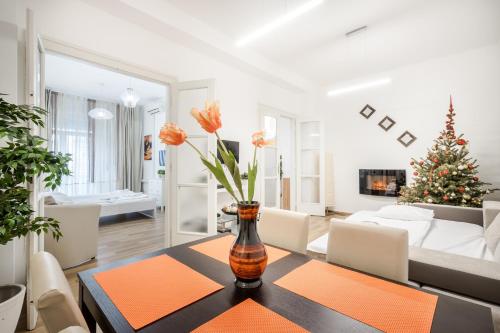 salon z wazą z pomarańczowymi kwiatami na stole w obiekcie Whitefield Apartment w Budapeszcie