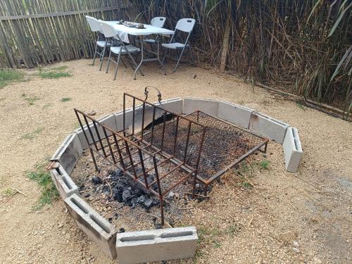 a fire pit in the dirt with a table and chairs at Cabaña Balneario buenos aires in Balneario Buenos Aires