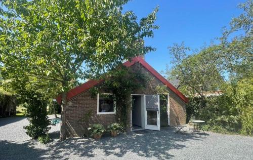 a small brick building with a window and a tree at Bed & Breakfast+ De Kooimolen in Dreumel