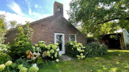 a small brick church with a clock tower on top at Bed & Breakfast+ De Kooimolen in Dreumel