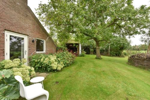 une chaise blanche assise dans l'herbe à côté d'une maison dans l'établissement Bed & Breakfast+ De Kooimolen, à Dreumel