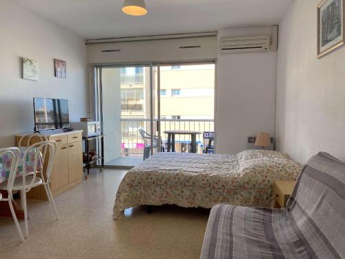une chambre avec un lit et une télévision et un balcon dans l'établissement Studio cosy avec balcon, climatisation, proche thermes - Balaruc-les-Bains - FR-1-553-99, à Balaruc-les-Bains