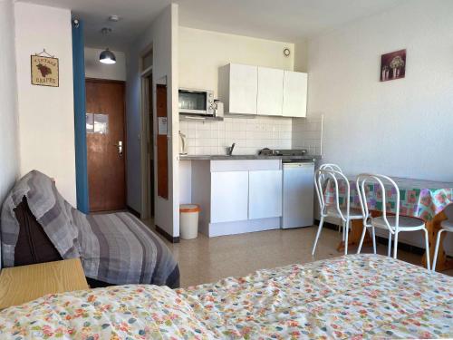 une chambre avec un lit et une cuisine avec des chaises dans l'établissement Studio cosy avec balcon, climatisation, proche thermes - Balaruc-les-Bains - FR-1-553-99, à Balaruc-les-Bains