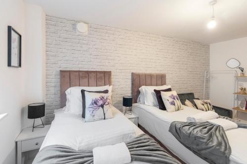 dwa łóżka w pokoju z ceglaną ścianą w obiekcie Tranquil Urban Haven w Londynie