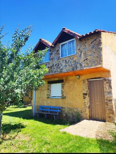 a stone house with a blue bench in front of it at Albergue Santa Ana in San Martín del Camino