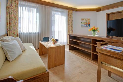 - un salon avec un canapé et une télévision dans l'établissement Hotel Restaurant Falken, à Baiersbronn