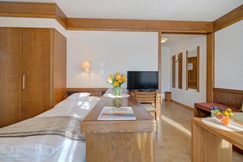 a room with a bed and a table with flowers on it at Hotel Restaurant Falken in Baiersbronn