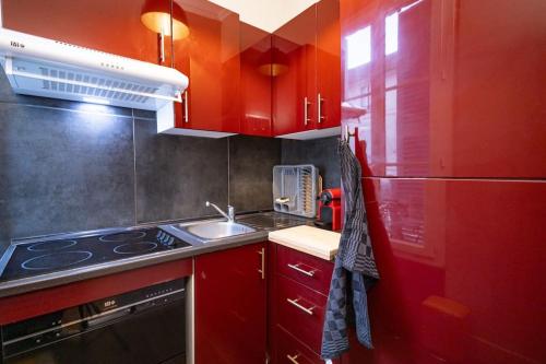 - une cuisine rouge avec évier et réfrigérateur dans l'établissement Le "Boudoir" Appartement de Charme climatisé en Plein Centre, à Bourges